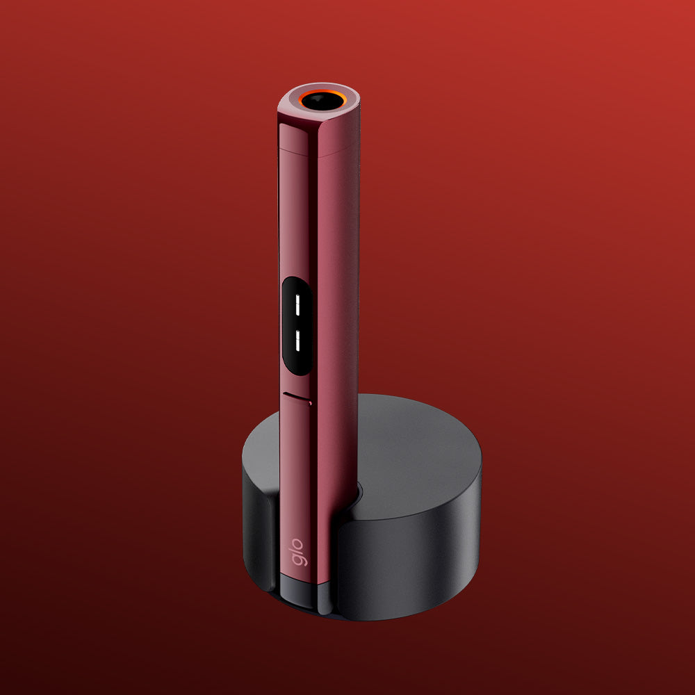 A sleek, red HILO Plus Pen with a circular tip stands upright in the glo™ HILO Plus Charging Dock, set against a gradient red background.