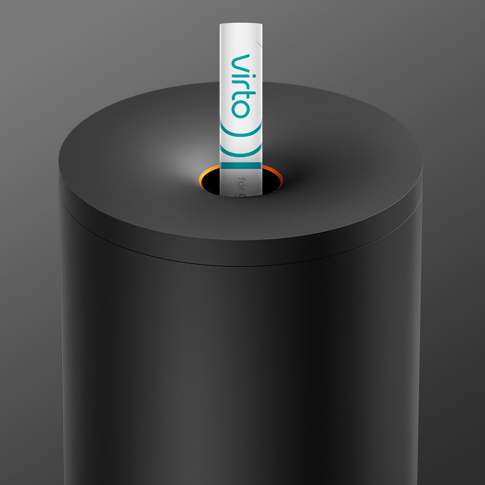 A cylindrical black glo™ Stick Bin with a circular top opening holds a white tube labeled "virto" in blue and gray. Its premium fabric cover provides sleek protection against daily wear, set against a smooth gray gradient background.