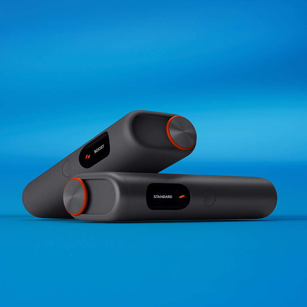 Two black glo™ HYPER PRO+ devices with orange accents rest on a blue gradient surface. Each device features a display showing settings labeled BOOST and STANDARD.