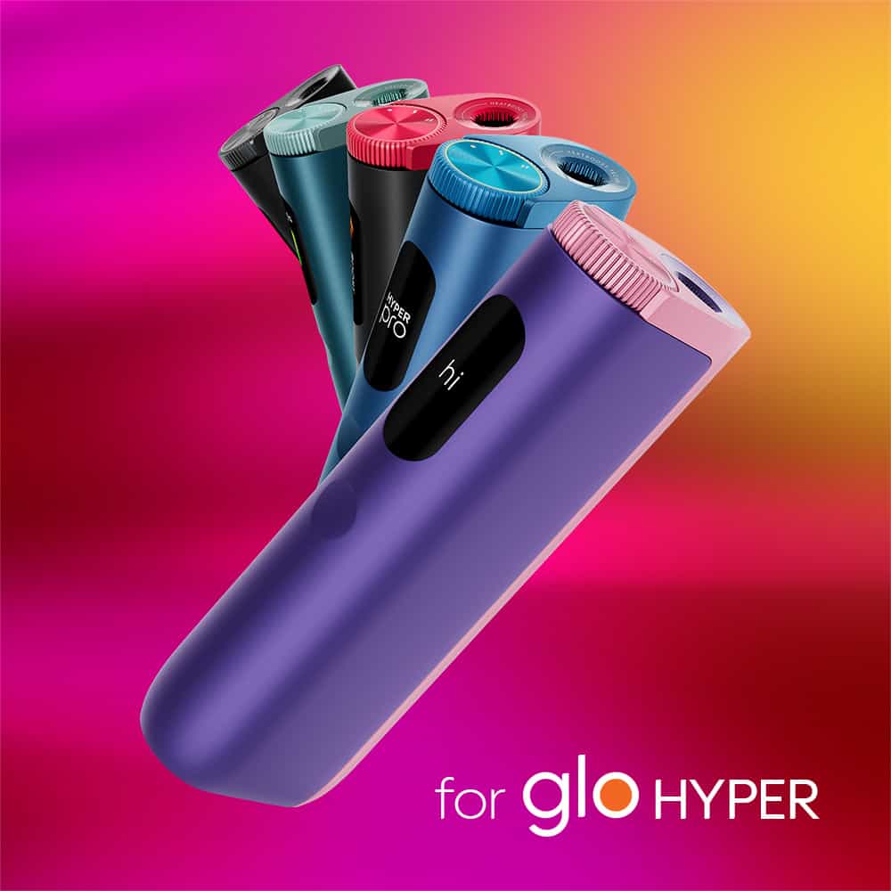 Sleek, colorful veo™ Tropical Twist devices with circular tops are arranged diagonally on a vibrant pink and yellow background, with the text “for glo HYPER” at the bottom.