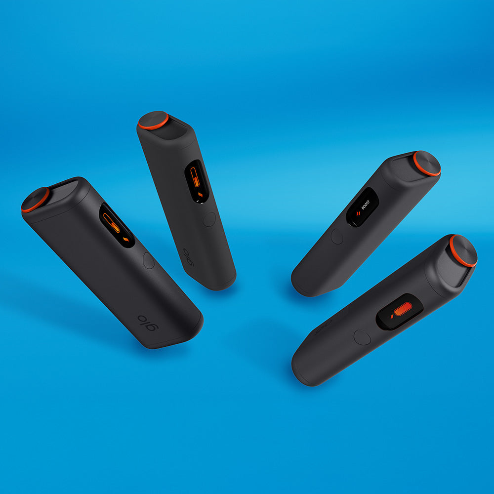 Four stylish glo™ HYPER PRO+ devices, black with orange accents, are arranged in a circle on a blue background. Each features a button and a small display or window on the front.