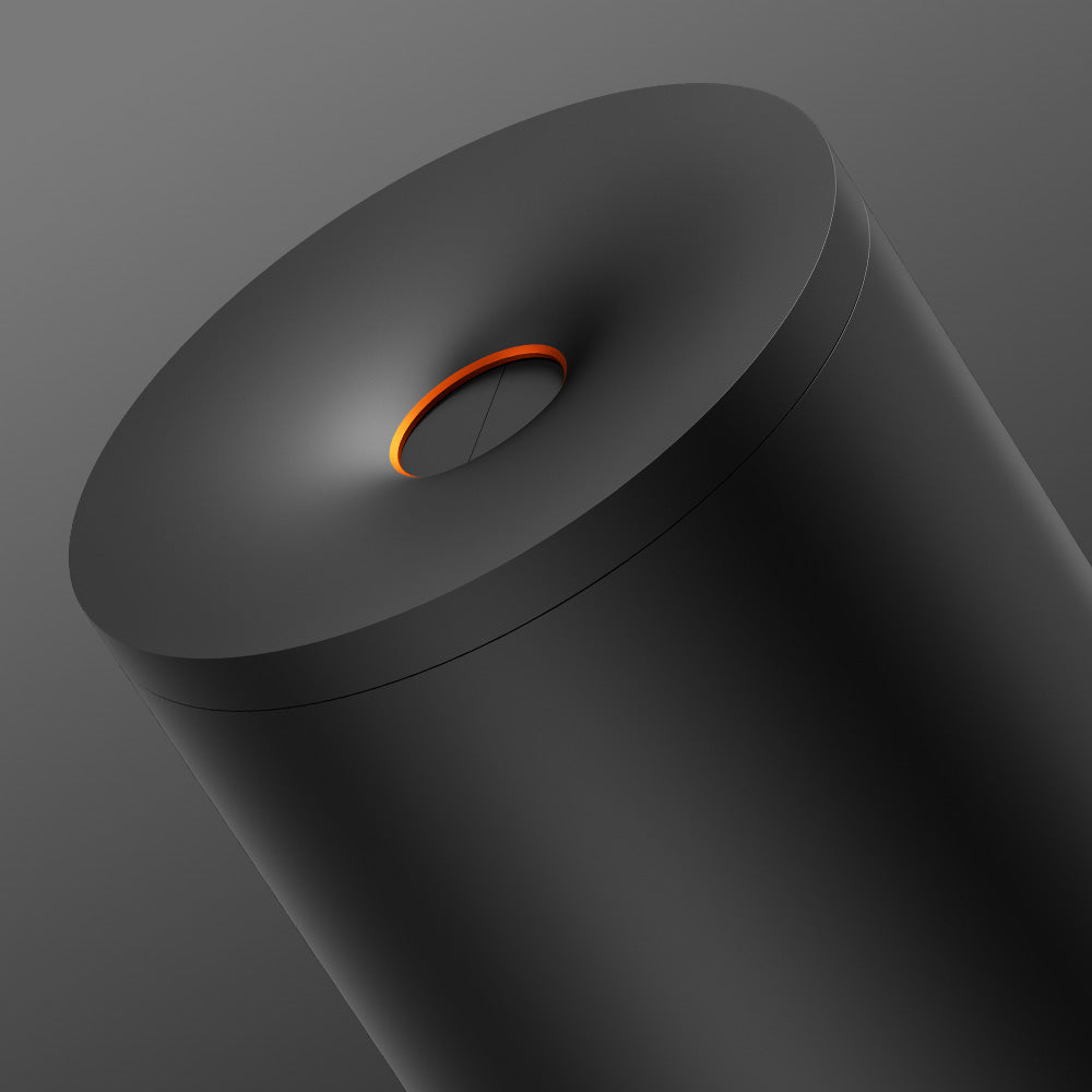 The glo™ Stick Bin is a sleek, cylindrical black container with a smooth matte finish and premium fabric cover, featuring an orange ring accent around a shallow concave center at the top for extra device protection.