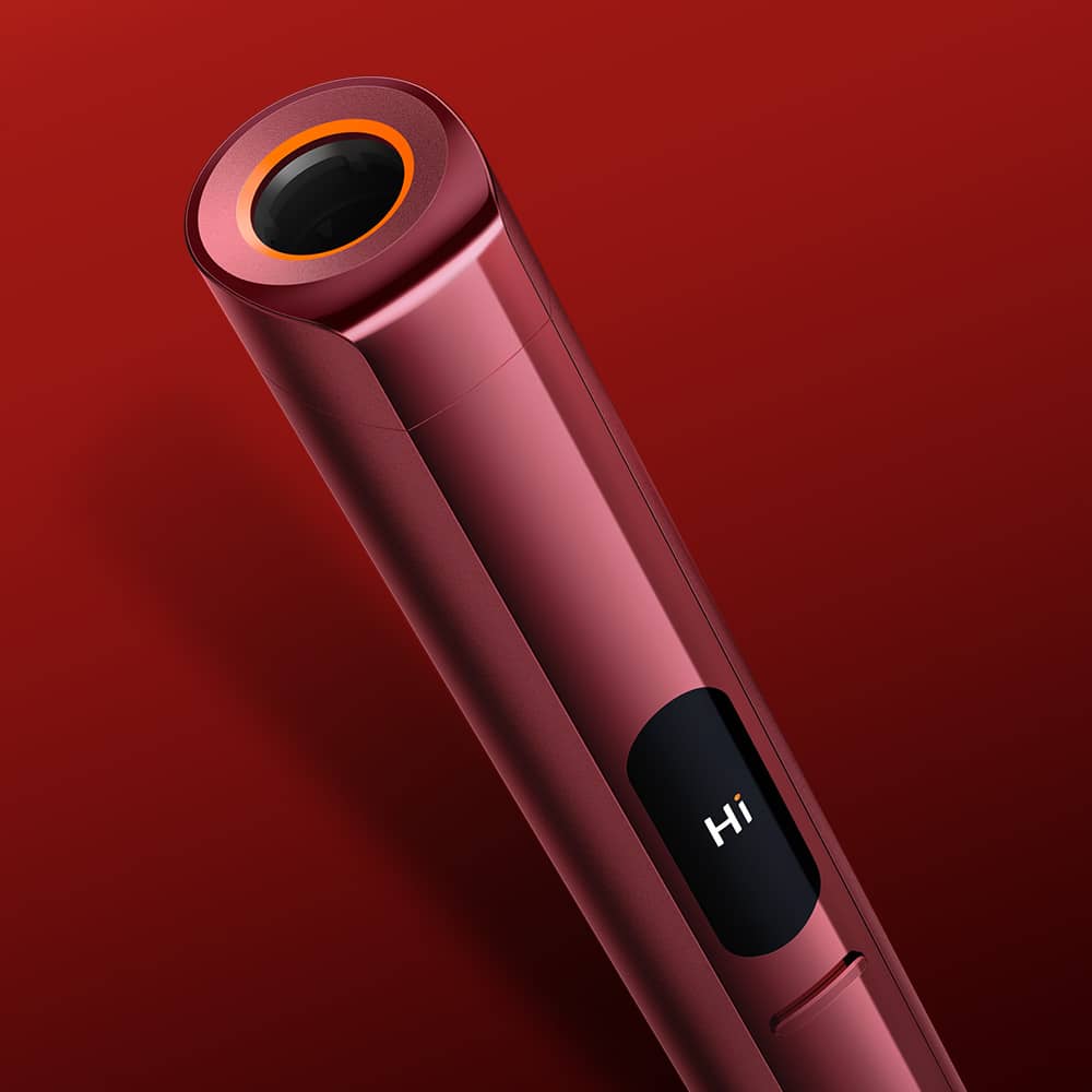 A sleek, metallic red electronic device with a circular black and orange top, shown against a red background. The device features a small digital screen displaying the word Hi.