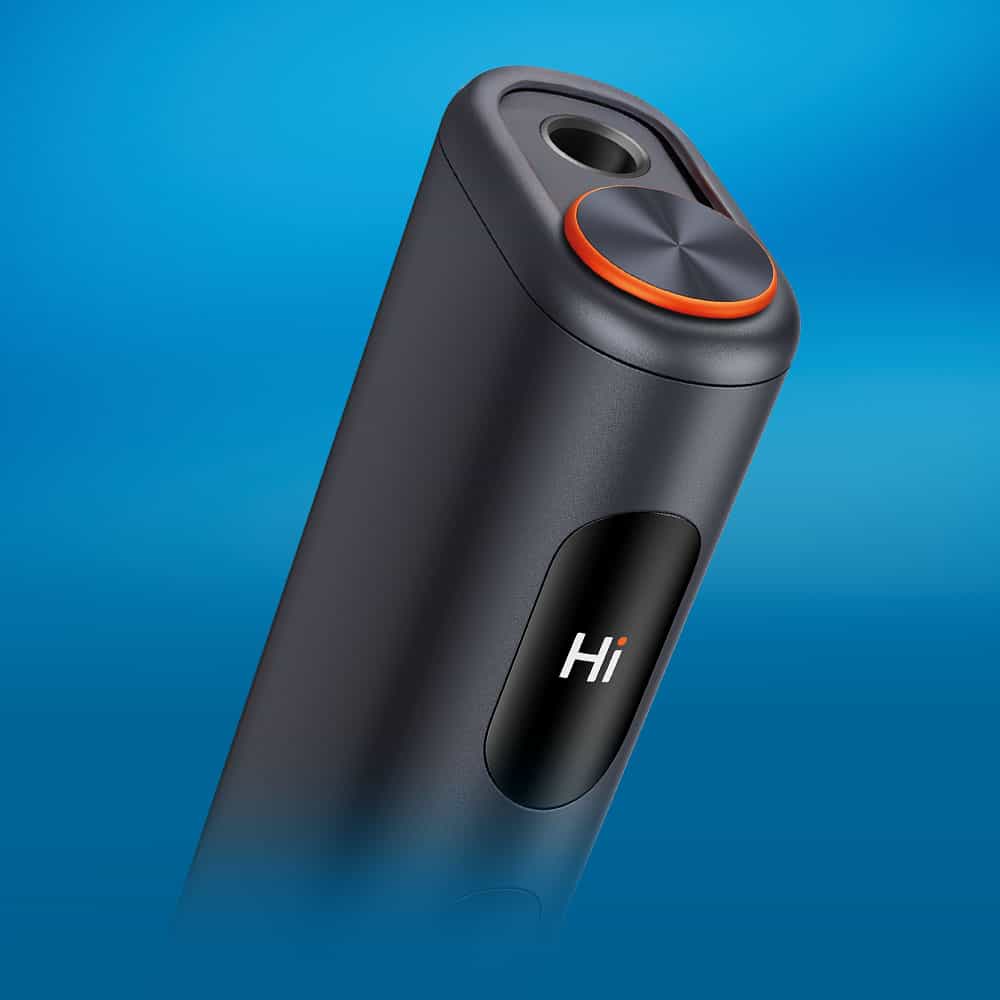 A close-up of a sleek, dark gray electronic device with an orange-accented circular button and the word Hi displayed on its surface, set against a blue gradient background.
